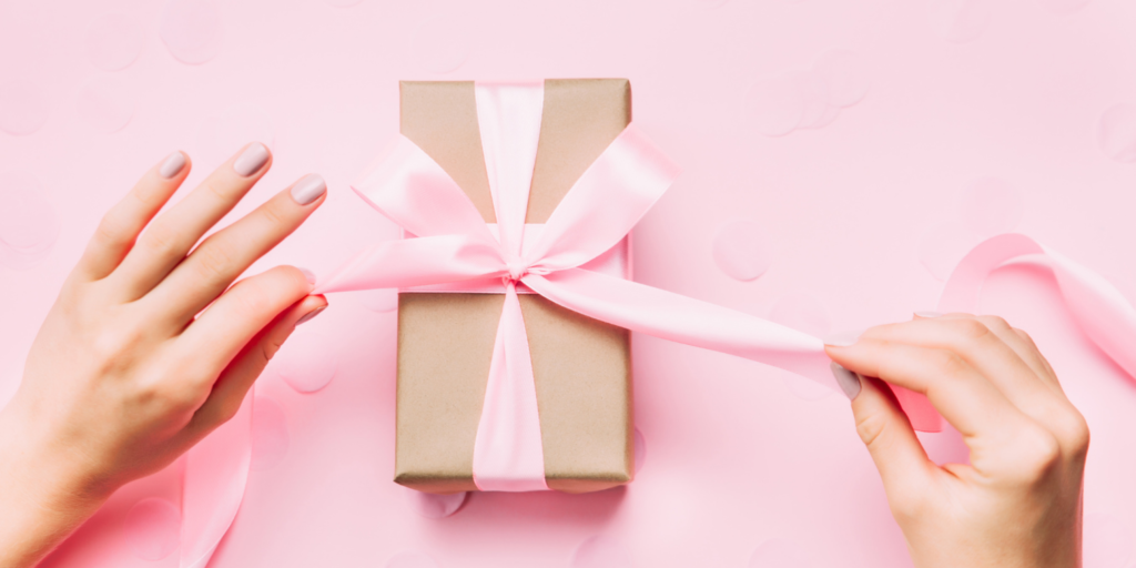 Tying a pink ribbon around a gift box