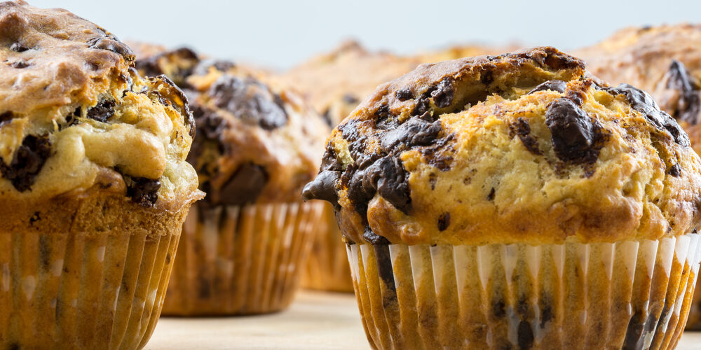 Delicious homemade chocolate chip muffins on wooden surface.